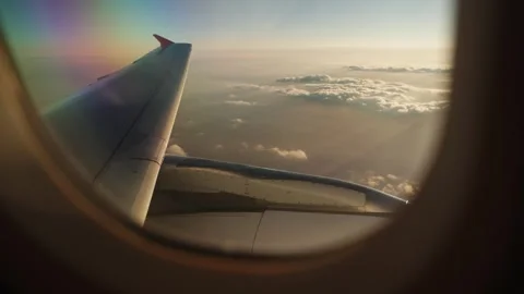 View from Airplane Window of Wing Above Clouds Illuminated by Golden Sunset Vídeos de archivo 346105785