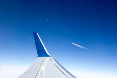 View from the airplane window to the wing and another plane flying by in the Stock Photos