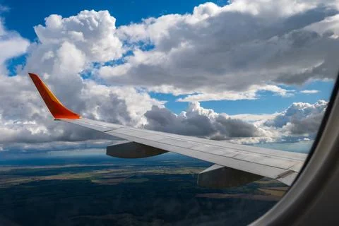 View from airplane window on wing and landscape with clouds on window durin.. Stock Photos