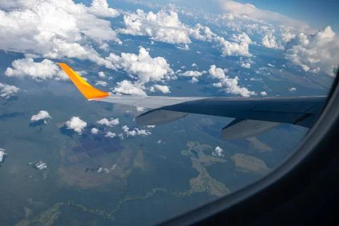 View from airplane window on wing and landscape with clouds on window durin.. Stock Photos