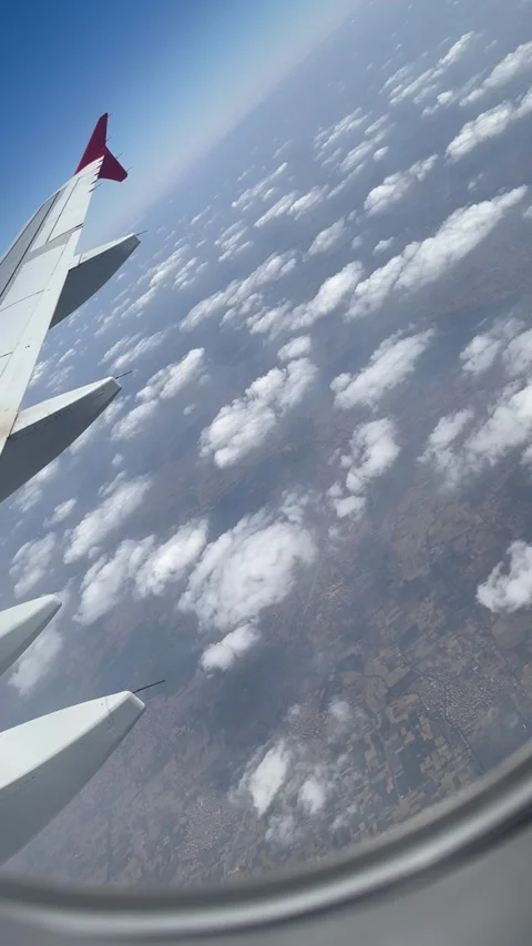 View from an Airplane Window of a Wing Flying Over Fluffy White Clouds Stock Footage 329193925