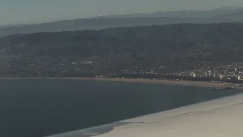 View from an airplane window of the wing over a coastal city Video stock 347739335