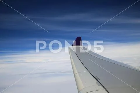 View from airplane window on the wing over the white cloud and blue sky in t Stock Photos