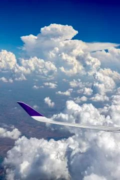 View from airplane window on the wing  over the white cloud and blue sky in t Stock Photos