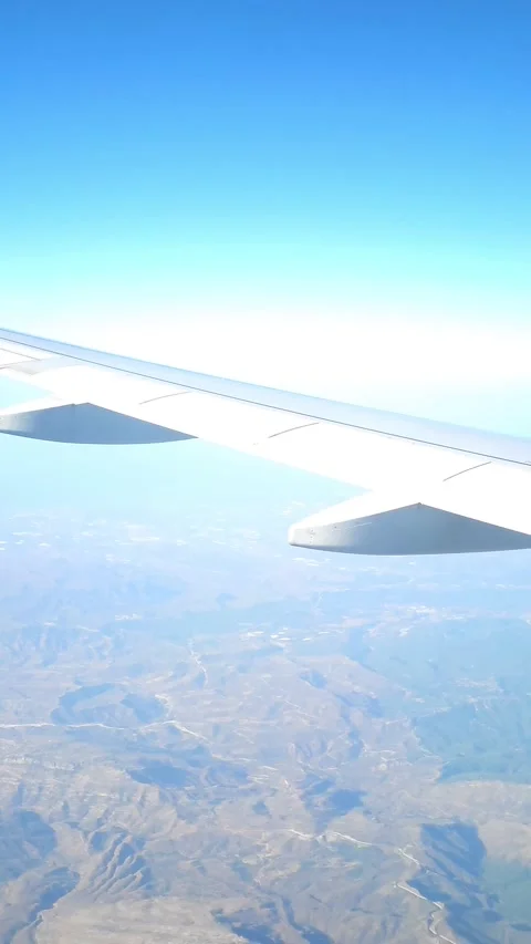 View of airplane wing and landscape below captured from a passenger window Stock Footage 299736826