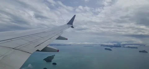 View from an airplane of a wing in clouds, with sights of islands below 動画素材 212792917