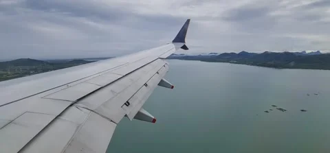 View from an airplane of a wing in clouds, with sights of islands below 動画素材 212793039
