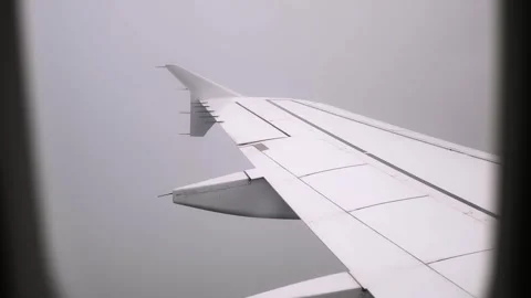 View on an airplane wing in clouds through a porthole. Cloudy sky background. A Video stock 338184839