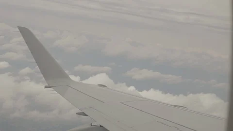 View of Airplane Wing Outside of Window Flying Through Clouds Above City Video stock 100837504