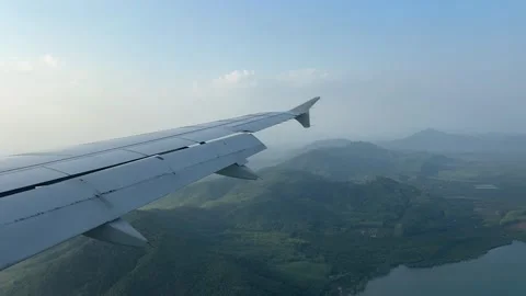 View of airplane wing from passenger window seat while flying over the sea Stock Footage 330589284