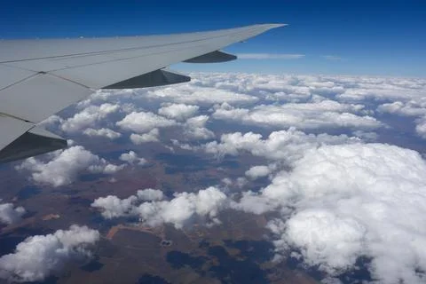 View of an airplane wing from a passenger window during flight above scattered c Stock Photos