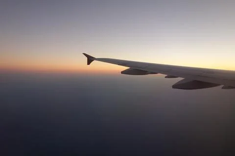 View of an airplane wing from a passenger window during flight above the sea at  Stock Photos