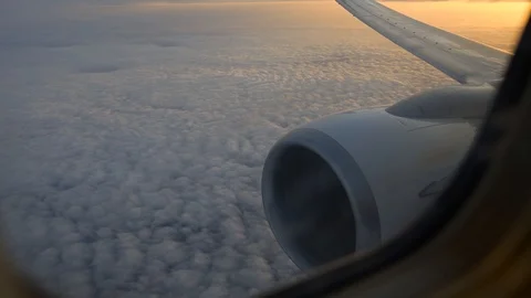 View of airplane wing through plane window. Flying above the clouds at sunrise. Stock Footage 101485407