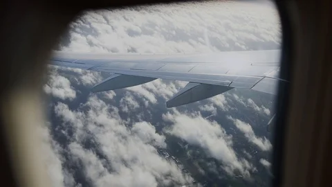 View of airplane wing through plane window. Flying above the clouds. Stock Footage 101485527