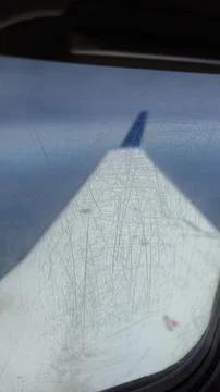 A view of an airplane wing through a scratched window glass. Stock Photos
