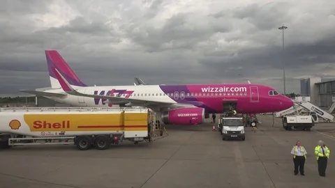 View of airport worker loading baggage on airplane busy runway trailer machine Stock Footage 82372547