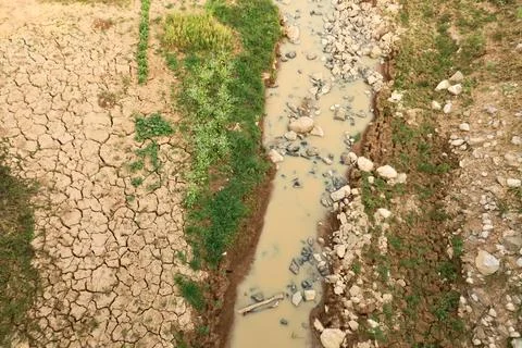 View onto an almost dried out riverbed, a small muddy stream of water next .. Foto stock