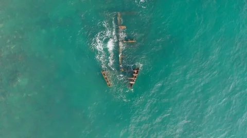 View along the hull of a sunken ship lying in shallow water near the beach Stock Footage 106351280