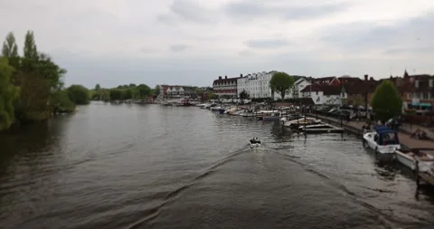 View along a river lined with buildings, moored boats, and people, with a small Stock Footage 308418451