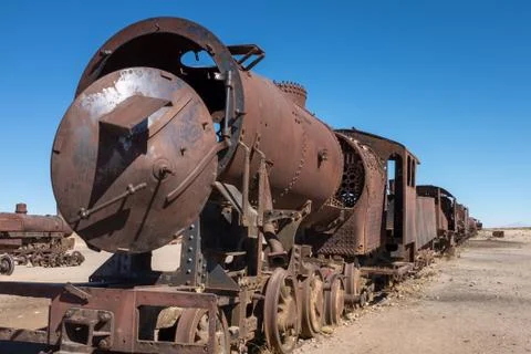 A view along the side of a rusting steam train and carriages slowly rot away at Foto stock