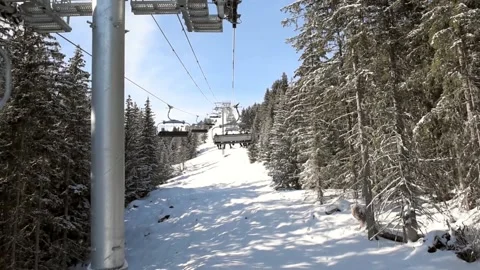 View of an alpine winter slope while traveling on chairlift through trees Stock Footage 194948154