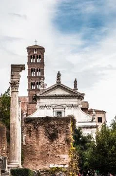 View on ancient cathedral between the trees with blue cloudy sky on the backg Stock Photos