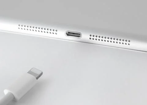 View of Apple Lightning cable and gadget on a white table with empty space, c Stock Photos