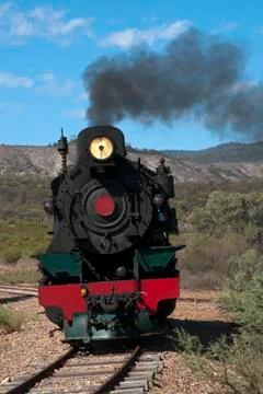 View of approaching restored steam engine with semi arid landscape in background Stock Photos