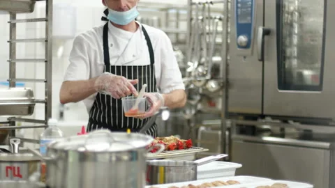 A view from around the corner to the work of a chef wearing a mask. Media Stock Footage 150932008