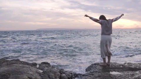 View from the back, beautiful woman dancing in the evening on a rock by the sea Stock Footage 254297997
