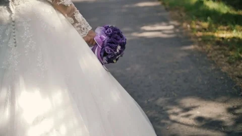View from the back on the bride with bouquet walk in the forest Stock Footage 73524373