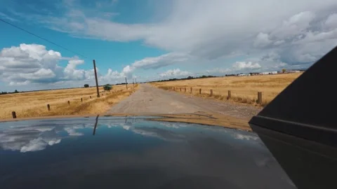 View from back of a car Driving on a Dirt Road Through Golden Dry Grasslands Und Stock Footage 318623056