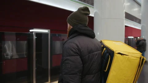 View from the back of delivery man with backpack who is waiting for a subway car Stock Footage 236089316