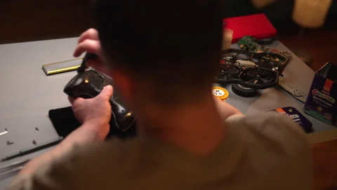 View from back of electronic technician assembling or repairing drone remote Stock Footage 302564484