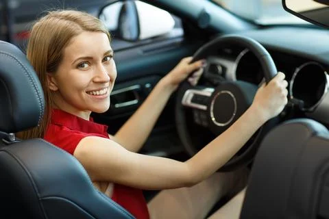 View from back of female customer testing expensive car in auto saloon Stock Photos