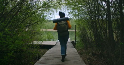View from the back: female going the old wooden bridge in the wood. Backpacker Stock Footage 131318735