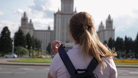 A view from the back of a female student with a backpack on her back. University Stock Footage 247127880