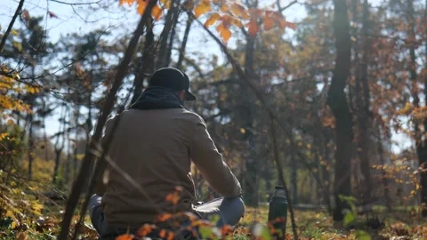 View from the back. a hipster man with a beard sits in a park in the forest Stock Footage 229858953