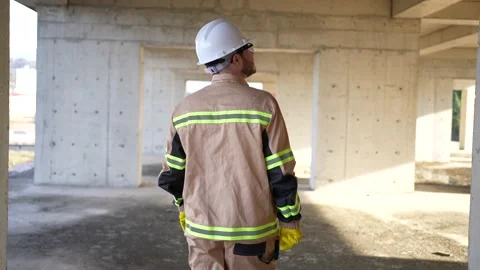 View from the back male builder engineer walking in a white helmet walks through Stock Footage 236376911
