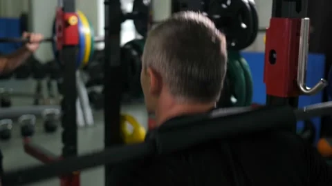 View from the back. Man crouches with a barbell 4K Slow Mo Stock Footage 100258289