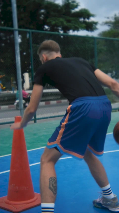 View from the back of a man exercising with a cone and a basketball Stock Footage 236985192
