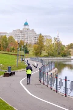 A view from the back of a man jogging in a park along a river canal. Man in s Stock Photos
