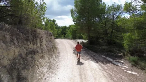 A view from the back, a man running along a mountain road. Stock Footage 286336013