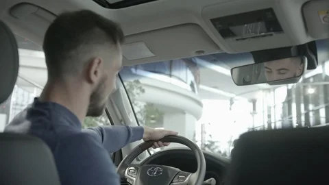 View from back man sitting in car and keeping wheel Video stock 100144396