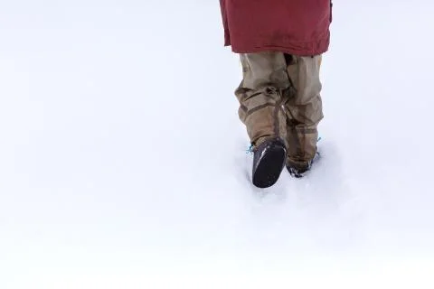 The view from the back of a man walking in the snow in rubber boots Stock Photos