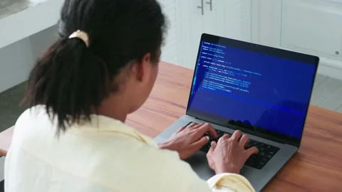 View from the back of a multitasking woman programmer, using laptop computer for Stock Footage 208107337