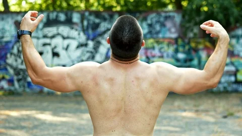 View from the back of silhouette of athletic man with a bare torso posing shows Stock Footage 119132584