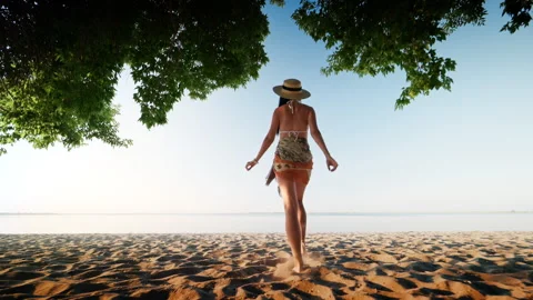 View from the back of a slim young girl in a swimsuit walking on the beach Stock Footage 312313316