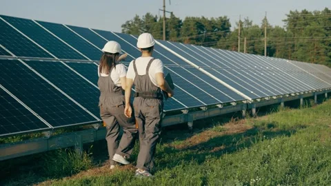 View from the back of specialists walking through a solar power plant Stock Footage 255981458