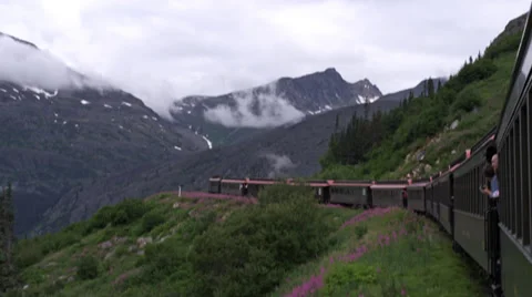 View from back of train, looking forward, as train passes through mountains in Stock Footage 36320164